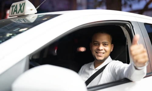 Friendly taxi driver giving thumbs up inside cab for safe taxi service in Dehradun